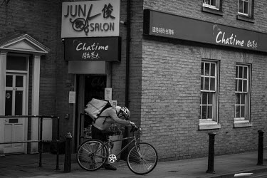 A Deliveroo cyclist collects an order from a Chinese take-away in Manchester's China Town on a Saturday evening during the coronavirus lockdown.