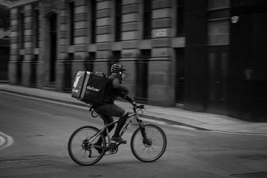 A Deliveroo cyclist delivering take-aways in an almost empty Manchester city centre on a Saturday evening during the coronavirus lockdown.