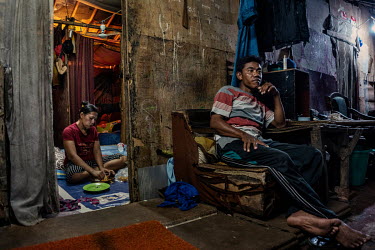 Marni (32), who works as rubbish sorter, eats dinner while her husband Durah (37), who picks rubbish from the Bantar Gebang landfill site, sits outside their shack in Ciketing Udik, a village of recyc...