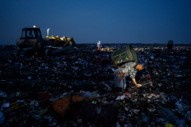 Rubbish pickers search into the night for recyclable plastic and other items amongst the freshly dumped loads of waste, brought in from Jakarta, at the Bantar Gabang landfill.