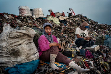 Rubbish pickers rest at dusk before they continue to search into the night for recyclable plastic and other items amongst the freshly dumped loads of waste, brought in from Jakarta, at the Bantar Gaba...