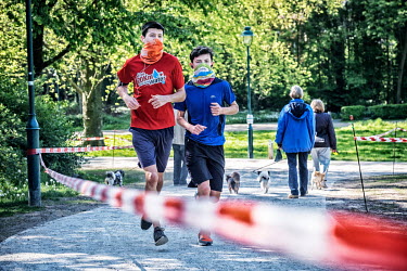 Two youths wear face coverings as they going jogging in a park.