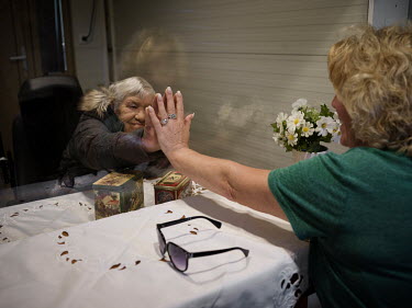 Thea Vroomen, 78, who lives in a care home, puts her hand next to her daughter's hand. Her daughter Karin Berenschot-Vroomen, 52 and her husband Jan Berenschot-Vroomen, 61 are meeting Thea in a mobile...