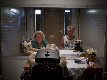 Thea Vroomen, 78, lives in a care home. Her daughter Karin Berenschot-Vroomen, 52 and her husband Jan Berenschot-Vroomen, 61 are meeting her in a mobile meeting room where they are separated by a scre...
