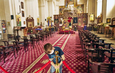 Vaclav (9) wearing a homemade face mask polishes the brass stanchions on Good Friday in Saints Cyril and Methodius Cathedral. Most churches and services are closed due to coronavirus outbreak. Most ch...