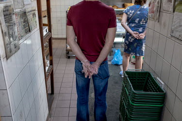 A man, wearing plastic gloves, waits in line to buy sweets for Iftar, the breaking of the Ramandan fast at the end of the day, at the Yasar Halim bakery in Green Lanes, which has a large Turkish and K...