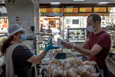 A man, wearing plastic gloves, buys sweets for Iftar, the breaking of the Ramandan fast at the end of the day, at the Yasar Halim bakery in Green Lanes, which has a large Turkish and Kurdish community...