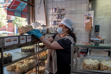 A shop assistant sells a cake to a customer buying food for Iftar, the breaking of the Ramandan fast at the end of each day of Ramadan, at the Yasar Halim bakery in Green Lanes, which has a large Turk...