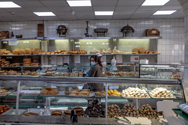 A woman, wearing a face mask, buys cakes and sweets for Iftar, the breaking of the Ramandan fast at the end of the day, at the Yasar Halim bakery in Green Lanes, which has a large Turkish and Kurdish...