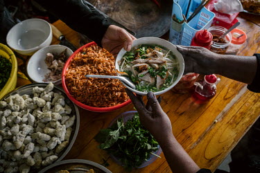 A customer receives a bowl of Pho (noodle soup) prepared in the canteen at Sapa's market. Black cardamom (Thao Qua) is an ingredient in the broth of a traditional Pho and much used in Vietnamese cuisi...