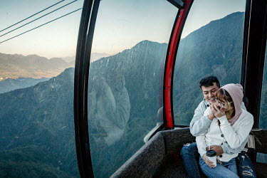 A couple taking in views of the Hoang Lien Son mountain range while on a 6282m-long cable car ride to Mount Fansipan. Built in February 2016 the cable car starts its journey from the foot of the mount...