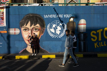 People pose and walk in front of protest murals painted on walls in Sadoon Street in the city centre.  Since the beginning of October 2019 huge anti-government protests have shaken the country. People...