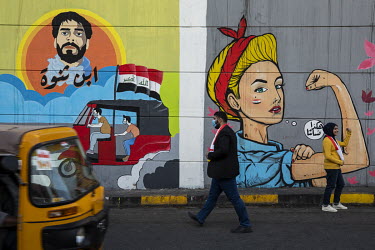 People pose and walk in front of protest murals painted on walls in Sadoon Street in the city centre.  Since the beginning of October 2019 huge anti-government protests have shaken the country. People...