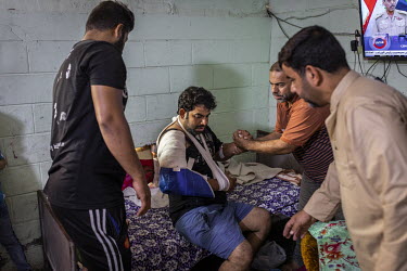 Relatives of a tuk-tuk driver help him lie down at his home in Sadr City the day after he was shot in his abdomen with a tear gas canister allegedly fired by security forces.   Since the beginning of...