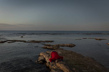 A fisherman prays on the shore as the sun sets on Benghazi's Mediterranean coast.