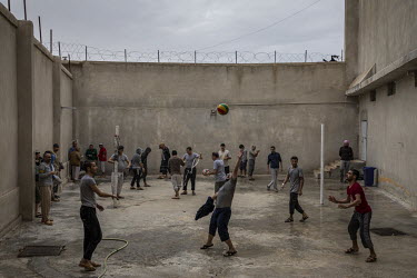 Suspected ISIS members, detained by Kurdish forces, during an exercise session in a high walled yard in a prison in northeast Syria.