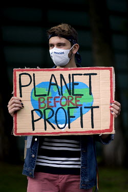 A student environmental activist holds a sign that reads: 'Planet Before Profit' during a protest against the startup of the coal-fired power plant Datteln 4 outside the Finnish Embassy. The Finnish e...