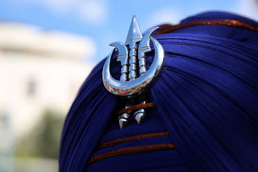 A Sikh Deg Tegh Fateh symbol on a man's turban.