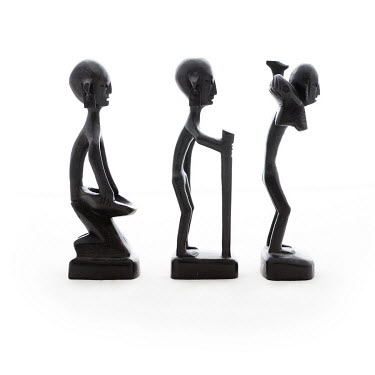 Three African wooden figurines photographed from the side, bought in Lusaka in 2014.