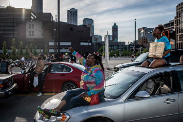 Two women sit on their vehicle during a demonstration protesting the killing by the police of George Floyd, an unarmed African-American.