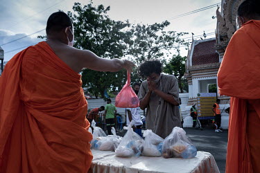 An unemployed man gives thanks as he recieves a food donation from a monk at the Wat Sawetachat Worawihan temple.