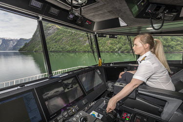Captain Anu Ernstsen, originally from Finland, on the bridge of the electric ferry Vision of the Fjords as it sails what is normally the popular route between Flam and Gudvangen in Sognefjordenon. Tou...