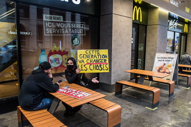 A woman holds a placard that reads 'This is the generation that will change things', as a couple, who have taken part in a Black Lives Matter protest rally, stop to rest outside of a McDonald's restau...