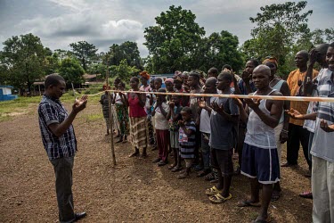 Residents of a village hit by Ebola pray while they stand behind a quarantine line.