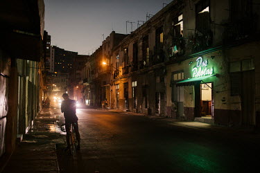 A man stops to light a cigarette while cycling through Havana Centro.