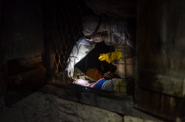 An Ebola burial worker collects a swab sample from the body of a suspected Ebola victim from a vilage near Kailahun.