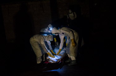 Ebola burial workers collect the body of a person who has died from suspected Ebola from a village near Kailahun.
