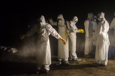 An Ebola burial team disinfect each other after collecting the body of a person who has died from suspected Ebola.