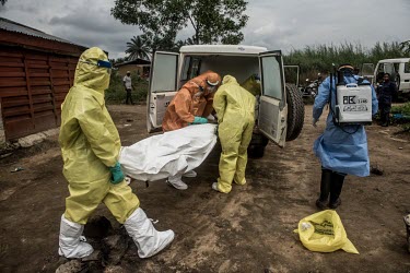 Workers in full personal protective equipment, load the body of a suspected Ebola victim into a hearse.