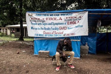 A man holds his head in his hands outside an Ebola screening centre.