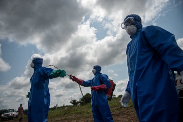 An Ebola burial team disinfect each othre's personal protective equipment after intering the body of an Ebola victim in a graveyeard near Makeni.