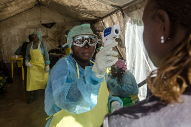 A nurse takes a woman's temperature in a triage tent at the Kenema government hospital during the Ebola outbreak.