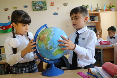 Pupils at school no. 220, which practices inclusive education where children with disabilities study together with the non-disabled, looking at a globe.
