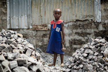 A young girl stands among a pile of stones holding a large heavy hammer. She breaks rocks, which are used in the construction industry, earn money to help add to her family's income. Manually breaking...