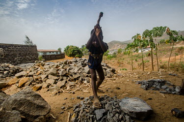A young boy swings a sledgehammer above his head as he breaks rocks into aggregate for the construction industry. Rock breaking is a big employer in Sierra Leone, but it is an industry riddled with ch...