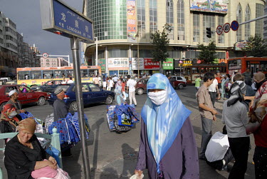 A Muslim woman walks past hawkers in the busy city centre.