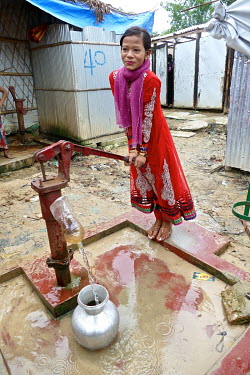 Rohingya refugee Showkat Ara (15) pumps water into a container in the refugee camp where she lives with both parents and seven siblings, having arrived nine months previously.  ''When military started...