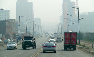 Smog creates a haze over a road as traffic moves through the city.