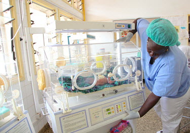A nurse, on a neonatal high care ward, operates an incubator for a premature baby being treated at the Simao Mendez central hospital.