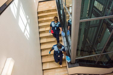 Part of the post-pandemic regime at the UN in Geneva, a team of masked cleaners disinfecting a staircase. They fpollow a set circuit of corridors and offices, starting over once it is finished, on a c...