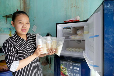 Huynh Thi Niem uses a breast pump to collect expressed milk which she keeps in a fridge before it is collected by a representative of the Da Nang milk bank.