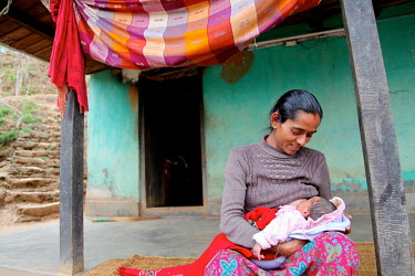 Sabina Kattel breastfeeding her 13 day-old daughter outside her home in Kettel Danda village.