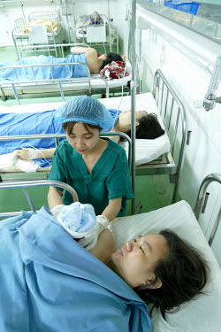 A nurse helps Huynh Thi My Hanh hold her new born baby that has just been delivered by c-section at the Da Nang hospital for women and children.