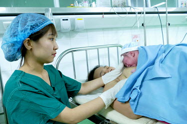 A nurse helps Huynh Thi My Hanh hold her new born baby that has just been delivered by c-section at the Da Nang hospital for women and children.