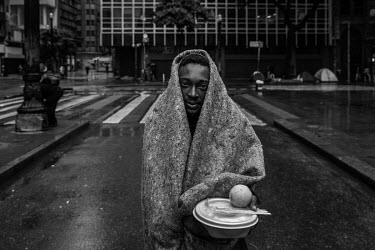 A man wrapped in a blanket holds a meal made by volunteers that was handed out at a soup kitchen in downtown Sao Paulo.