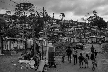 People carry away meals and hygiene products that have been distributed by members of an evangelical church to the residents of a squatter camp in the northern part of Sao Paulo. With the economic cri...